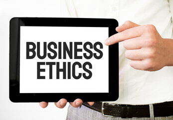 Text BUSINESS ETHICS on white paper plate in businessman hands on the white bakcground. Business concept