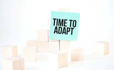 Text TIME TO ADAPT writing in green card cube ladder. White background. Business concept