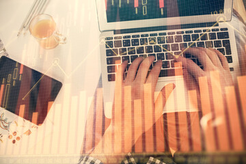 Double exposure of man's hands typing over laptop keyboard and forex chart hologram drawing. Top view. Financial markets concept.