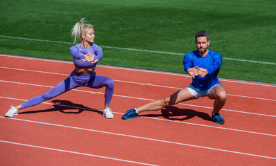 fitness sport man and woman warming up and stretching together on outdoor stadium racetrack wearing sportswear, coach