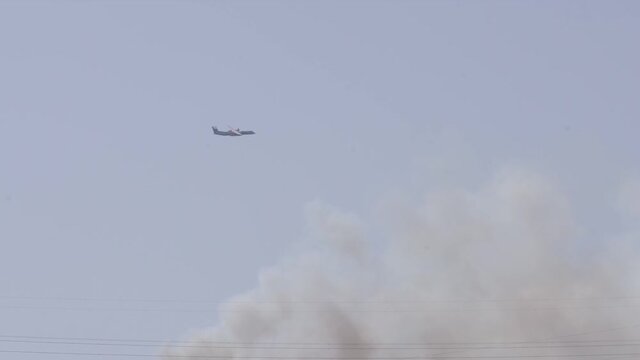 Bombardier Q400 flying over a bush fire on a sunny day, summer drought