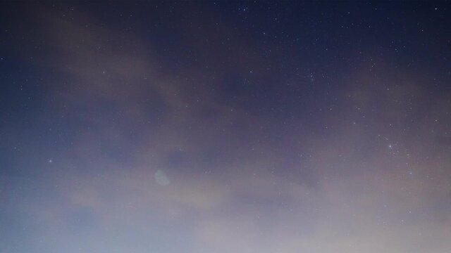 Time lapse of a sky of stars rotating counter clockwise on a winter night with light cloud cover while airplanes zip through the sky