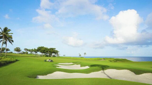 Golf course with green grass and sand pits by the sea. Dominican Republic golf course on a sunny summer day.