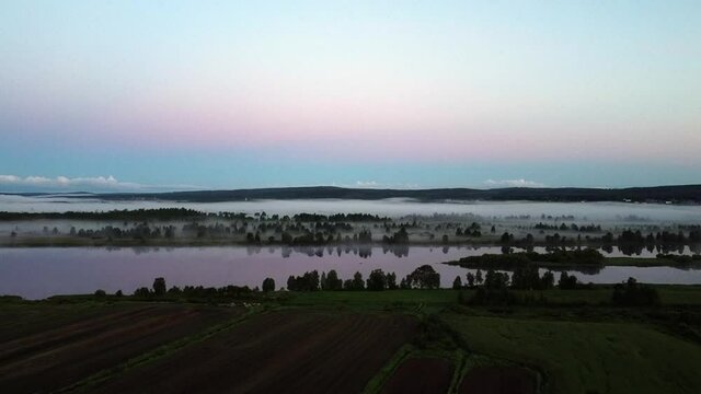 Foggy Agricultural Acres alongside Finland longest river, Tornio river , aerial dolly in shot 
