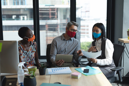 Diverse colleagues wearing face masks working together at modern office