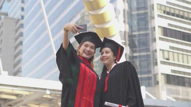 Two happy women in graduation gowns making selfie, Capturing happy moments.
