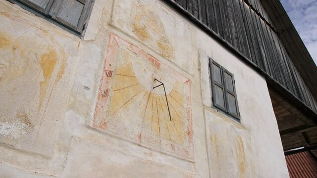 sundial fresco painted on old farm house in village in Slovenia, dolly shot