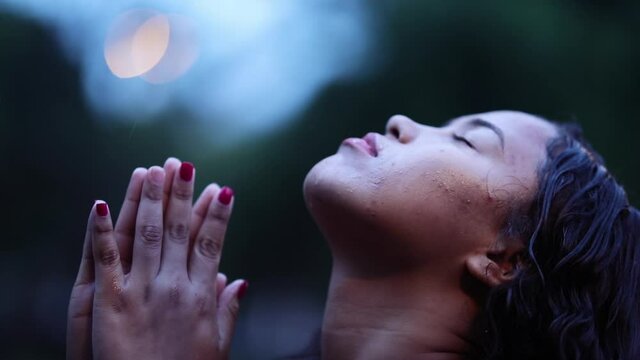 Young woman praying in the rain feeling the presence of God