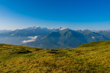 Scenic summer view on snowy grossglockner peak and nordlicher bockkarkees in sunny day with green meadows, pine tree forests, hills, blue sky. Europe alps in austria