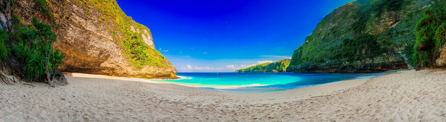 Azure beach with rocky mountains and clear water of Indian ocean at sunny day / A view of a cliff in Bali Indonesia