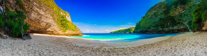 Fototapeta na wymiar Atuh Beach with crystal clear azure water on background mountain landscape and blue summer sky. Bali, Indonesia