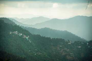 View of Himalayas mountain ranges with visible silhouettes through the fog from Mall Road of Shimla city, Himachal Pradesh. It is a popular hill station for holidays in India