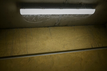 Spiderwebs under a fluo light in an concrete emergency exit.