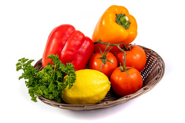 a basket of red pepper, lemon, tomatoes and parsley cooking vegetable ingredients isolated on white

