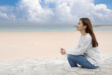 沖縄のビーチで音楽を聴く若い女性