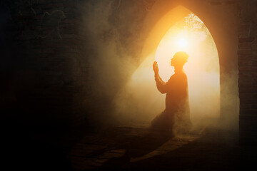 Silhouette religious of muslim male praying in old mosque with lighting and smoke background