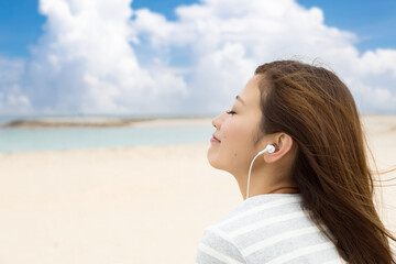 沖縄のビーチで音楽を聴く若い女性
