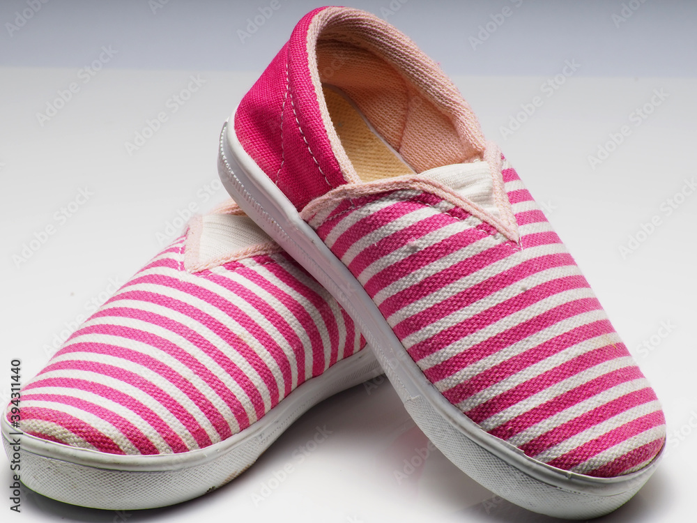 Wall mural close up shot of a pair pink shoes with white stripe pattern on an isolated background