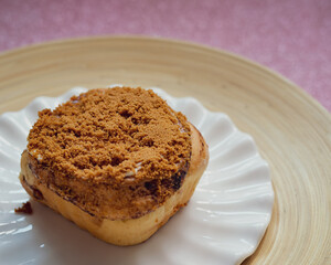 Cinnamon rolls with Lotus BIscoff crumbs topping on a white and bamboo plate.
