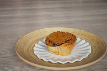 Cinnamon rolls with Lotus BIscoff crumbs topping on a white and bamboo plate.