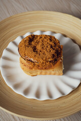 Cinnamon rolls with Lotus BIscoff crumbs topping on a white and bamboo plate.