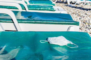 A disposable face mask on chaise longue at the beach