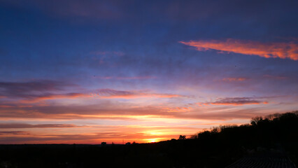 Amazing sunrise in rural scene. Dramatic sky with sunbeam and stratus clouds over the silhouette of hill on the horizon.