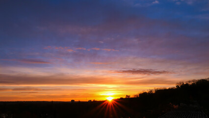 Amazing sunrise in rural scene. Dramatic sky with sunbeam and stratus clouds over the silhouette of hill on the horizon.