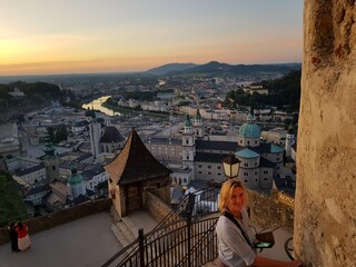 Über den Dächern von Salzburg schaut eine junge Frau direkt in die Kamera und lächelt im...