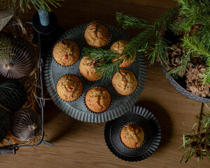 Top view of Christmas cupcakes and homemade paper Christmas ornaments and vintage decorations in Scandinavian or nordic style. Beautiful flat lay in natural green and wooden tones