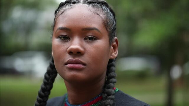 Dramatic black African woman looking at camera. Portrait diverse ethnic girl staring at park
