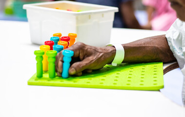 Occupational therapy: hand function training in stroke patient by using various colors pegboard at a therapy room in the hospital