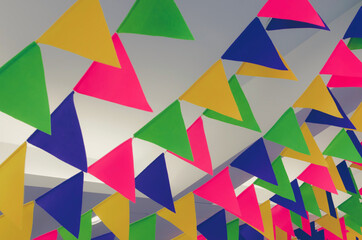 Obraz premium Colorful triangle flags hanging under ceiling. Toned image. Festival background.