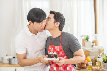 Asian homosexual gay man couple celebrate birthday party with cake together at home. Handsome guy LGBTQ lover have a romantic moments together. Same-sex marriage and LGBT couple relationship concept.