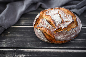 Round loaf of freshly baked sourdough bread. Artisan bread on dark table. Rustic sourdough bread.