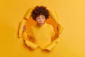 Embarrassed shocked young Afro American woman stares with bugged eyes, keeps mouth opened, wears...