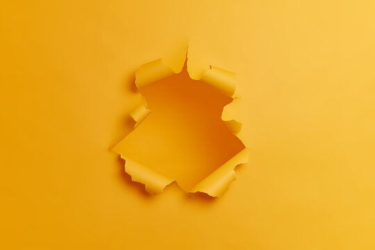 Big paper hole in center of yellow background. Blank space to insert your advertising content promotion or text information. Torn ripped studio wall. Breakthrough concept. No people in shot.