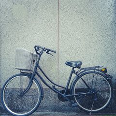 A bicycle parked in front of a concrete wall. Toned image.