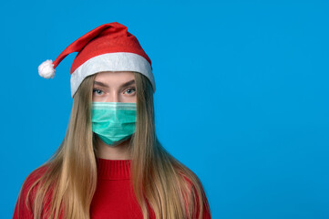 Fototapeta na wymiar Girl in a medical mask with a Santa hat