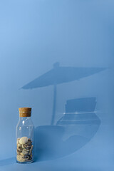
sand and shells in a bottle with a cork on a blue background