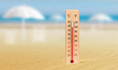 Sea coast at hot summer day. Wooden thermometer in the sand. Ambient temperature plus 39 degrees celsius