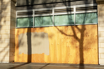 Exterior of business, store, restaurant boarded up with plywood sheets. Plywood shutters prevent...