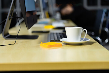 Business office desk with coffee cup and city light bokeh background.