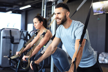 Young couple on body training with trx in gym.