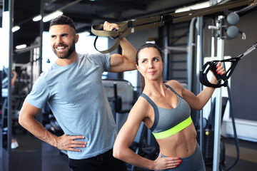 Young couple on body training with trx in gym.