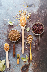 Various dried legumes in spoons top view flat layon dark concrete background