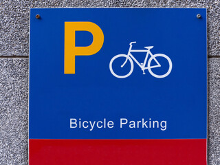 A blue bicycle parking sign on a wall.