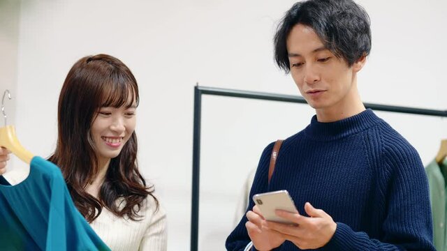 アパレルショップでスマホを見るカップル