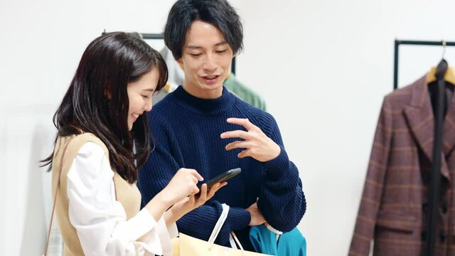 アパレルショップでスマホを見るカップル