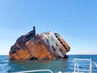 hull of a shipwrecked ship in the black sea against the blue sky on a Sunny day.